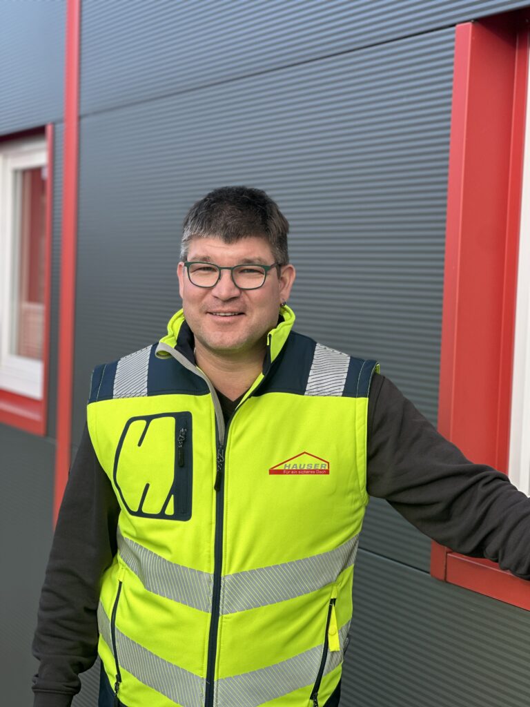 Alexander Hauser in Arbeitsmontur vor dem Unternehmenssitzgebäude